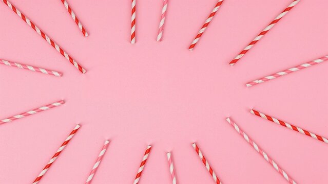 Colorful heart-themed paper straws arranged on a pink backdrop for a love-inspired event.