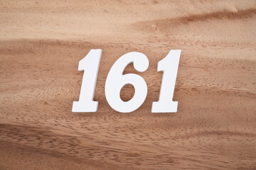 The numbers are made of white painted wood placed on a brown wooden floor.
