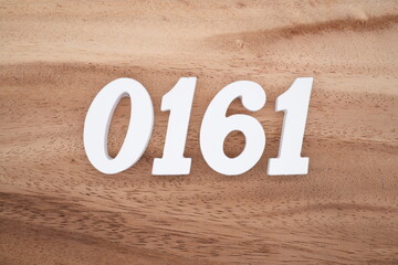 The numbers are made of white painted wood placed on a brown wooden floor.