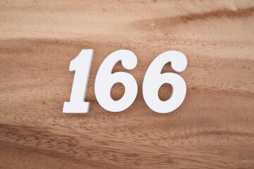 The numbers are made of white painted wood placed on a brown wooden floor.