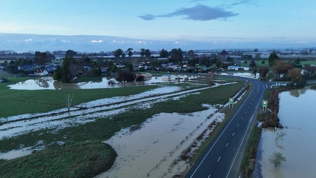 Aerial view of waterlogged fields and submerged houses reflecting the overcast sky, with a road barely visible, Motueka, Tasman region, New Zealand.