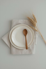 A neutral-toned ceramic plate, light beige fabric napkin, wooden spoon, dried wheat stalks, and soft gray background create a minimalist, earthy, and elegant aesthetic.