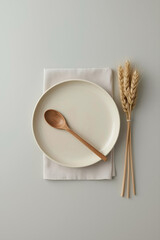 A neutral-toned ceramic plate, light beige fabric napkin, wooden spoon, dried wheat stalks, and soft gray background create a minimalist, earthy, and elegant aesthetic.