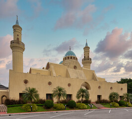 Fototapeta premium Ash Shaliheen Mosque, Bandar Seri Begawan, Brunei Darussalam. Distinctive yellow facade, twin minarets, and blue dome under a soft, cloudy sky