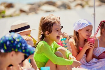 Children enjoying a sunny day at the beach with drinks and laughter. Concept of emotional learning...