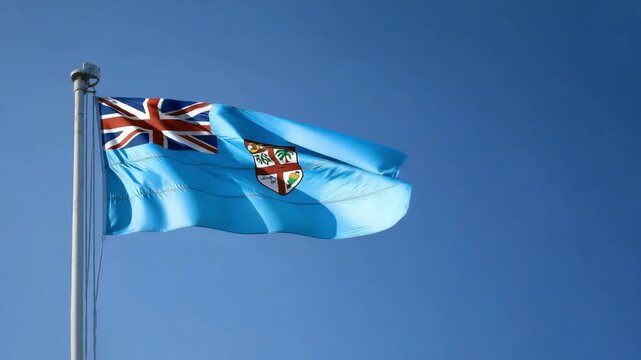 The flag of Fiji is prominently displayed, fluttering in the wind beneath a vibrant blue sky, showcasing the island nation's pride.