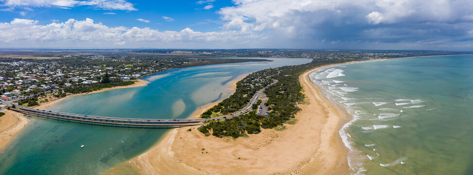 Aerial panorama of a bridge over a coastal river separating a town and a narrow beach