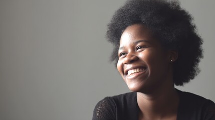 Portrait of a young Black woman smiling warmly, softly lit by natural window light.