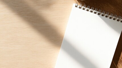 Minimalist wooden desk with blank notebook under soft morning light, clean beige background.