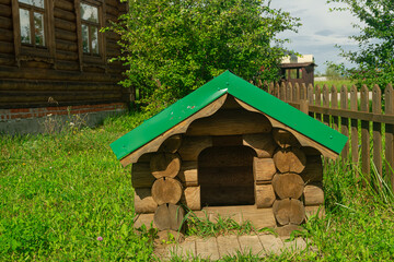 Doghouse made of wooden logs, with a green metal roof, in the Tartar style
