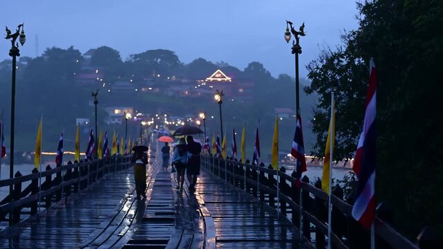 KANCHANABURI THAILAND Aug 14,2024 Mon ethnic women walk and carry things on their heads on the Mon wooden bridge, the longest wooden bridge in Mon village Sangklaburi Kanchanaburi,Thailand.