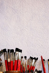 Closeup of paintbrushes with red handles, shiny metal ferrules and dense black tufts, neatly...