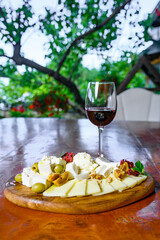 A plate of Cheese, figs and almonds with a glass of wine