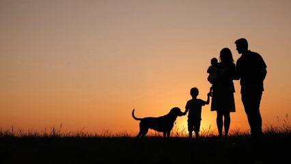 Silhouette showing a cheerful family of four plus their pet dog in front of a dusk sky, designed with room for writing