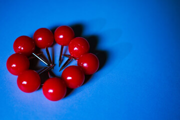 Bright red push pins arranged in a circular pattern on a bold blue background. The vibrant contrast...