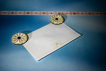 A clean flat lay of a blank card with floral corner accents, held by elegant clips on a blue background. Ideal for creative branding, journaling, or announcement templates.