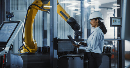 Electronics Manufacturing Technician Working on a Laptop Computer at a Factory Space. Asian...