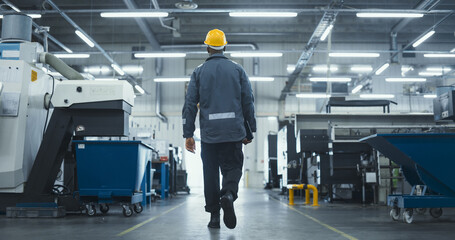 African Male Worker in a Yellow Hard Hat and Workwear Walks Through a Modern, Automated AI Factory...