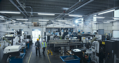 Fototapeta premium Establishing Shot Of Professional Diverse Employees Working at an Industrial Production Plant. Specialists Producing Metal Components with Heavy Duty Tools and CNC Milling Machines