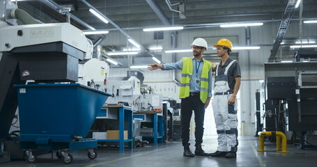 Technical Inspector Meeting a Young Shift Supervisor at an Industrial Production Plant. Men Discuss Operational Strategies in a Modern Factory. They Wear Hard Hats and Safety Vests