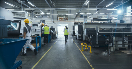 Establishing Shot Of Professional Diverse Employees Working at an Industrial Production Plant. Specialists Producing Metal Components with Heavy Duty Tools and CNC Milling Machines © Gorodenkoff