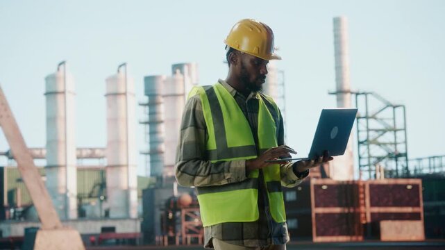 Industrial engineer working on laptop at refinery