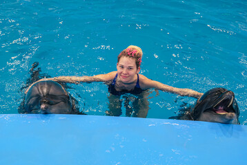 Woman interacts with dolphins in a blue pool during a marine park encounter
