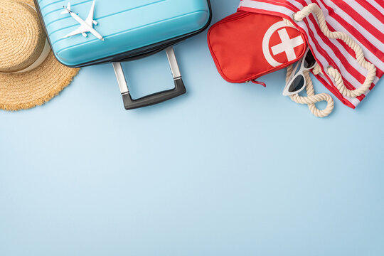 A composition of summer travel essentials including a suitcase, sunhat, first aid kit, and more