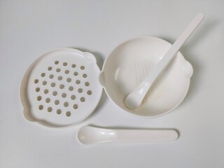 White Set of children's bowls, grater and spoons on the white background. Baby tableware. Nutrition...