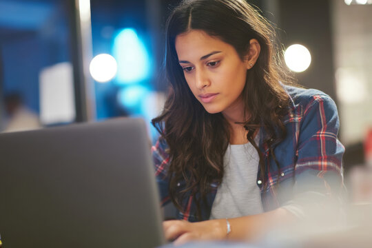 A young Hispanic woman writes product launch email drafts, tailoring the voice and urgency of messaging for targeted customer groups.