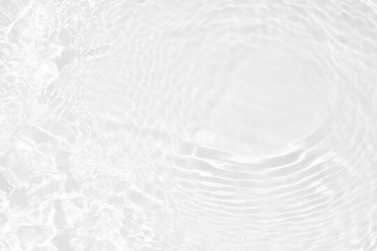 White water with ripples on the surface. Defocus blurred transparent white colored clear calm water surface texture with splashes and bubbles. Water waves with shining pattern texture background.