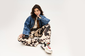 Stylish young woman models cow print pants in trendy studio setup