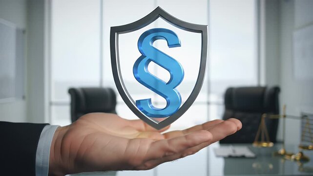 Man Holding Transparent Shield with Paragraph Symbol Over a Clean Office Table with Scale of Justice and Modern Window View