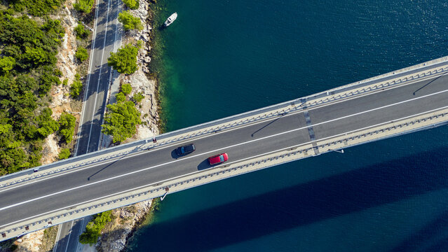 Aerial view of cars traversing a modern bridge, framed by the deep blue sea and verdant coastline, Dubrovnik, Dubrovnik-Neretva County, Croatia.