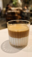 vertical photo of close up of a hot flat white coffee with two layers, brown layer of coffee and white layer of milk in a glass with copy space