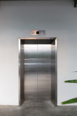 Elevator front door. Glossy stainless steel surface and clean concrete floor in front. Modern...