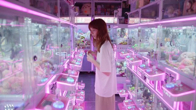 Young woman playing claw crane game in arcade