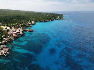 Aerial drone view of the dramatic cliffs of Negril, Jamaica, with turquoise Caribbean waters, lush vegetation, and stunning sunsets, an unforgettable tropical paradise on the island&rsquo;s west coast


