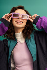 Stylish young woman exudes confidence in trendy sporty outfit against turquoise backdrop