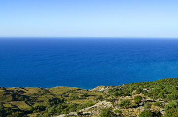 A beautiful blue ocean with a mountain in the background. The sky is clear and the sun is shining