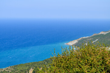 A beautiful blue ocean with a mountain in the background. The sky is clear and the sun is shining