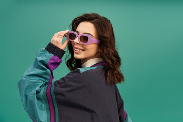 Stylish young woman showcases sporty fashion against a vibrant turquoise backdrop
