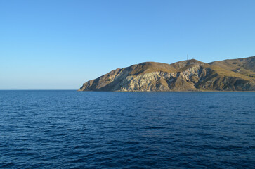 Fototapeta premium Rocky Island Coastline with Deep Blue Sea and Clear Sky