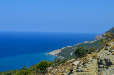 A beautiful blue ocean with a mountain in the background. The sky is clear and the sun is shining
