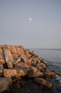 Moonrise Over Rocky Seashore at Dusk