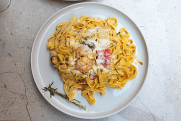 Delicious seafood fettuccine served on a white plate with herbs and cheese
