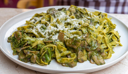 Delicious homemade pasta dish with pesto, mushrooms, and vegetables served on a white plate