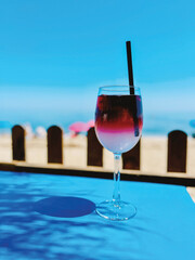 Cocktail on blue table with shadow of palm tree leaf at the beach under a blue sky. Andalucia, Spain.