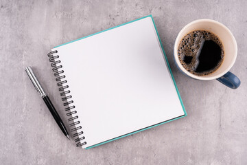 Top view of blank notepad and cup of coffee