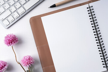 Top view of blank notepad with purple flower and pen